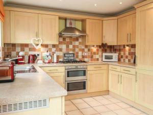 a large kitchen with wooden cabinets and appliances at Stunning Seaviews - Beach House - Jacuzzi Bath tub in Littlestone-on-Sea