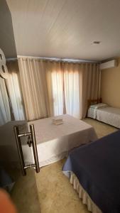 a bedroom with two beds and a window with curtains at Pousada Floripes in Morro de São Paulo