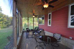 a covered porch with chairs and tables and a ceiling fan at Cuyuna Lake Cabin Retreat in Ironton