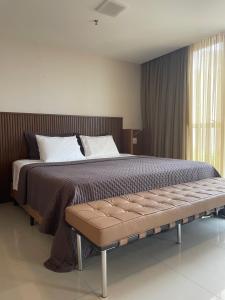 a bedroom with a bed with a bench in it at Flat Jade Hotel Brasília in Brasilia