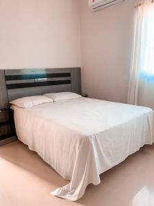 a bedroom with a white bed with a wooden headboard at CASA EM PORTO DE GALINHAS in Porto De Galinhas +19 photos