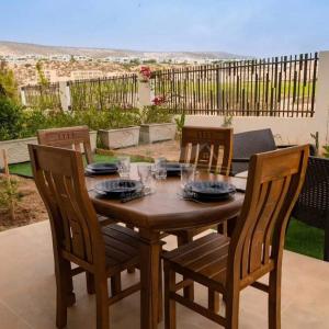 una mesa de madera y sillas en un patio en Studio vue golf Taghazout Bay Tamourit en Agadir