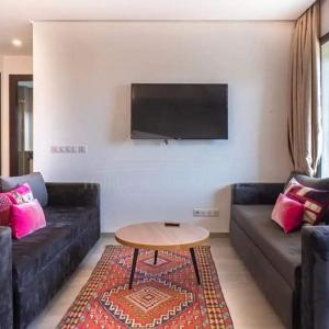 sala de estar con sofá, mesa y TV en Studio vue golf Taghazout Bay Tamourit en Agadir