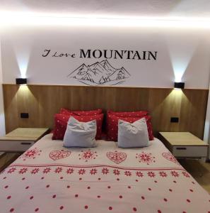 a bed with red pillows and a sign that says i love mountain at Moderno appartamento con giardino in Carisolo +44 photos