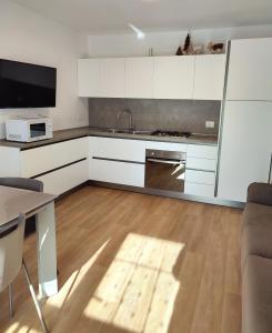una cucina con armadi bianchi, lavandino e tavolo di Appartamento con giardino a Carisolo
