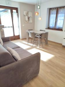 sala de estar con sofá, mesa y sillas en Appartamento con giardino en Carisolo