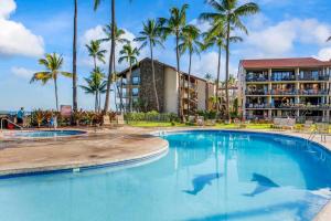 a swimming pool in front of a resort with palm trees at Papakea E206- Updated Papakea oceanview condo, all the amenities in Kahana