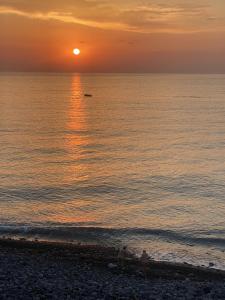 a sunset over the ocean with people on the beach at Dimora di Toosa - Near Taormina in Riposto