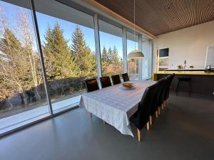 comedor con mesa, sillas y ventanas grandes en Villa by the lake Elliðavatn - Birta Rentals, en Reikiavik