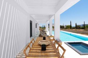 a pool with wooden benches next to a swimming pool at Seafish Villa, 2 Luxury Villas at Lachania Beach in Lachania