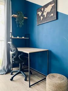 een kantoor met een blauwe muur met een bureau en een stoel bij Cocoon citadin : Appartement 2 pièces au coeur d'Evry in Évry-les-Châteaux