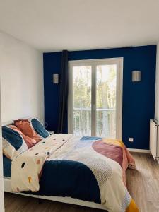 1 dormitorio con paredes azules y 1 cama con sábanas coloridas en Cocoon citadin : Appartement 2 pièces au coeur d'Evry, en Évry-les-Châteaux