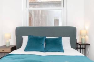 1 cama con almohadas azules en un dormitorio con ventana en Relaxing Oasis 1BR by the Sea by Sullivan Stays, en Brighton & Hove