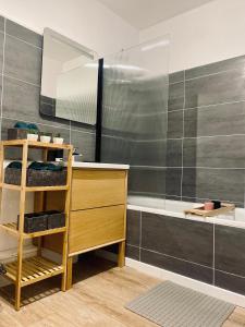 een badkamer met een wastafel, een spiegel en een bad bij Cocoon citadin : Appartement 2 pièces au coeur d'Evry in Évry-les-Châteaux