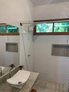 een witte badkamer met een wastafel en een douche bij Loft da Árvore nas Falésias em Cumuruxatiba in Prado