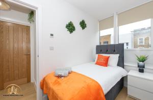 a bedroom with a bed with an orange blanket at Hephaestus Apartment - The Craftsman of Town in Southampton
