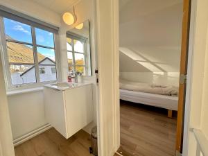 um quarto com uma cama, um lavatório e uma janela em House in Fuglafjørður em Fuglafjørður