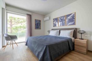 1 dormitorio con cama, ventana y silla en SeaLife Grand Penthouse Varkiza, en Vari