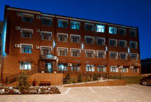 a large red brick building with lights on it at Alex Residence Hotel in Volzhskiy