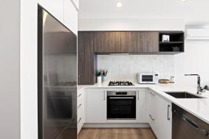 a white kitchen with a sink and a stove at Seaside Serenity at Bask Retreats in Mount Maunganui