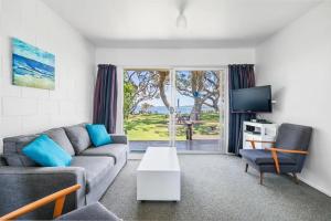 a living room with a couch and a tv at The Sands Motel in Tutukaka