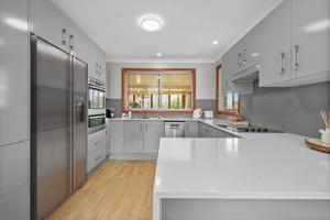 a large kitchen with white counters and stainless steel appliances at Ocean Breeze Vincentia by Book Jervis Bay in Vincentia