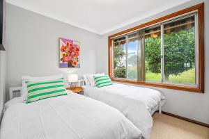 two beds in a room with a window at Ocean Breeze Vincentia by Book Jervis Bay in Vincentia
