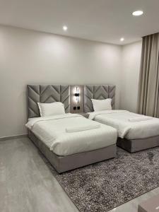 two beds in a bedroom with white walls at جادا للشقق المخدومة Jada in Al Khobar