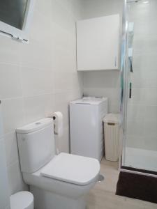 a white bathroom with a toilet and a shower at Siente el mar in Villajoyosa