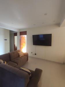 sala de estar con sofá y TV de pantalla plana en Apartments, en Chiclayo
