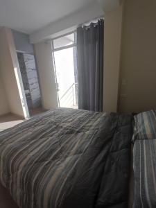 um quarto com uma cama e uma grande janela em Apartments em Chiclayo