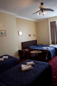 a hotel room with three beds and a table at Rose Court Hotel in London