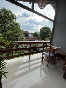 um quarto com uma varanda com uma mesa e uma janela em Aconchego Penedo em Penedo