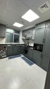 a kitchen with gray cabinets and a white tile floor at Luxury 2 bedroom new brand in Ajman 