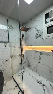 a shower in a room with white marble walls at Luxury 2 bedroom new brand in Ajman 
