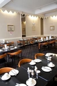 uma sala de jantar com mesas e cadeiras com chapéus em Rose Court Hotel em Londres
