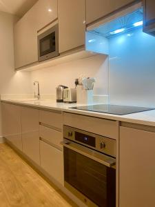 een keuken met witte kasten en een fornuis met oven bij Modern & Luxury Flat in Sutton