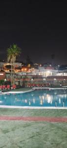 a large swimming pool with red umbrellas at night at Relax in pasito blanco camping house in Maspalomas