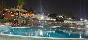 una piscina por la noche con sillas y un edificio en Relax in pasito blanco camping house, en Maspalomas