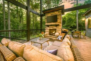 a screened in porch with a couch and a fireplace at New Modern Farmhouse w Jacuzzi BBQ Arcade in Broken Bow