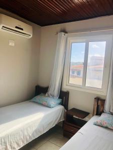 1 dormitorio con 2 camas y ventana en Duplex Beira-mar em condomínio / Búzios-RN, en Nísia Floresta