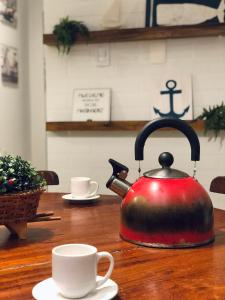 czajnik do herbaty siedzący na drewnianym stole z dwoma kubkami w obiekcie Duplex Beira-mar em condomínio / Búzios-RN w mieście Nísia Floresta