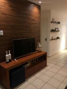 sala de estar con TV de pantalla plana en una pared de madera en Duplex Beira-mar em condomínio / Búzios-RN, en Nísia Floresta