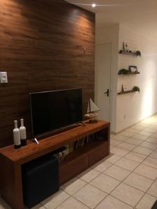 a living room with a flat screen tv on a wood wall at Duplex Beira-mar em condomínio / Búzios-RN in Nísia Floresta