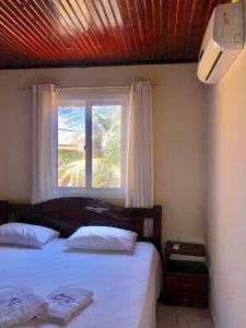 um quarto com uma cama e uma janela em Duplex Beira-mar em condomínio / Búzios-RN em Nísia Floresta