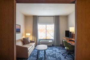 Fairfield Inn & Suites by Marriott Chillicothe في تشيليكوث: غرفة في الفندق مع أريكة وكرسي ونافذة