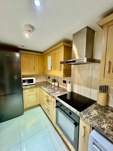 a kitchen with wooden cabinets and a stove top oven at NewDay Property - Chelsea in London