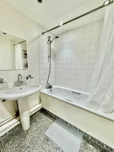 a bathroom with a sink and a bath tub and a mirror at NewDay Property - Chelsea in London