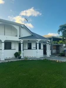ein weißes Haus mit Rasen davor in der Unterkunft Au Moulin Paradisiaque in Port-Louis