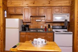 una cocina con armarios de madera y electrodomésticos blancos en Nantahala Resort cabin, POOL OPEN, horseback riding, game room, gym, restaurant on site en Bryson City